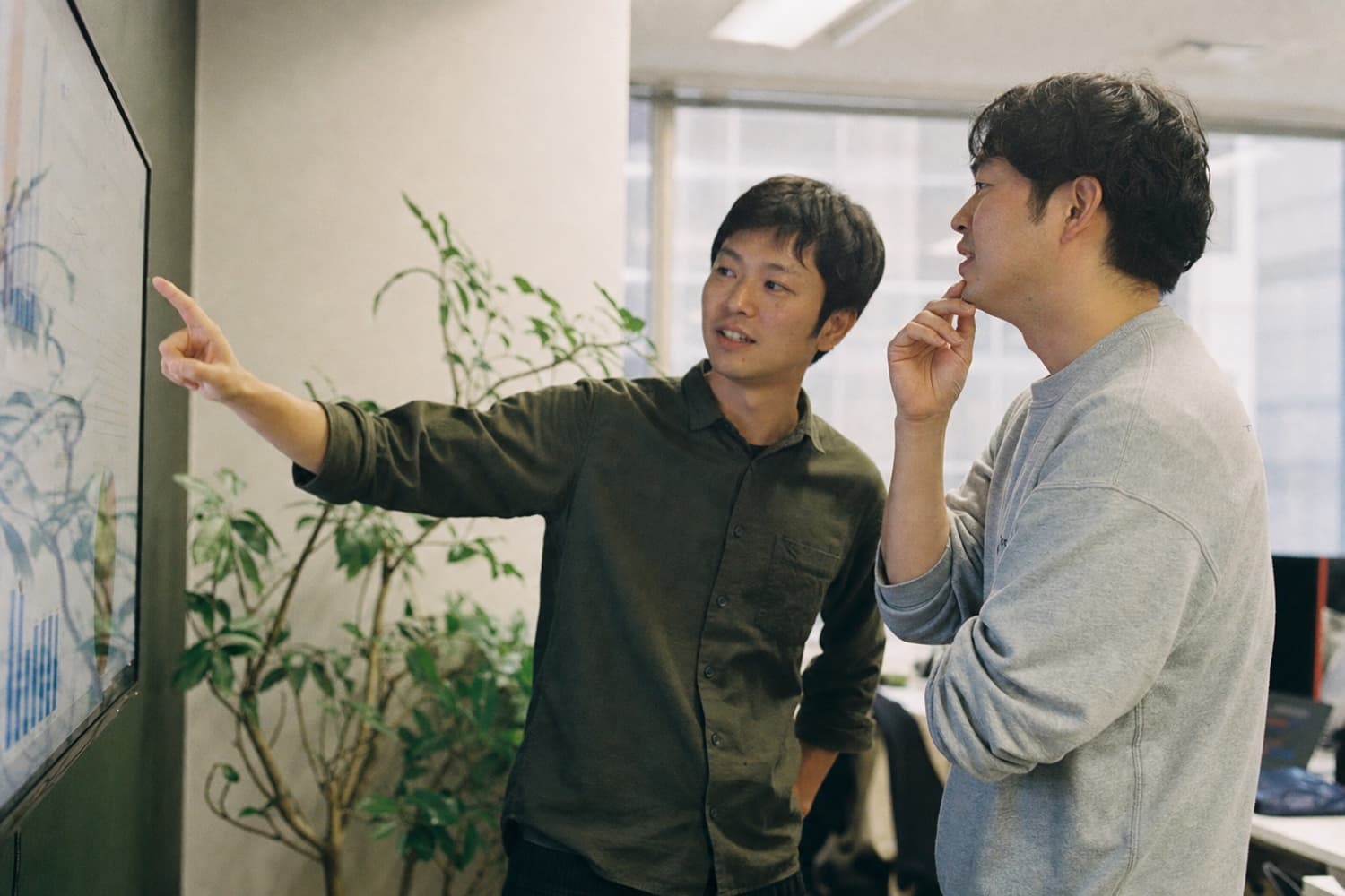 Team members pointing at data on a large screen as they discuss